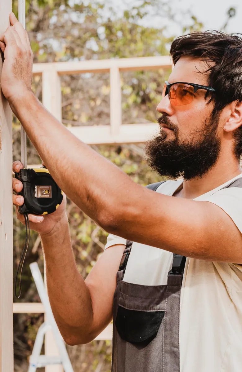 ADU construction worker measuring wood frame during backyard ADU build in Los Angeles